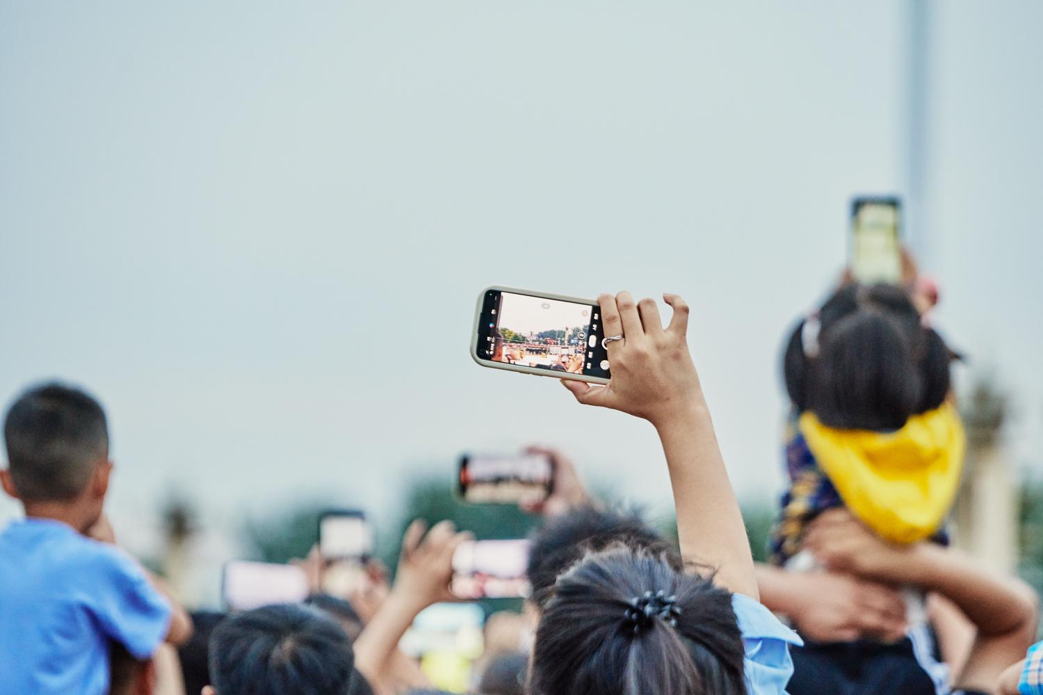 Multitud grabando un evento en directo con smartphones, representando el uso de My FanCam para crear vídeos centrados en una persona.