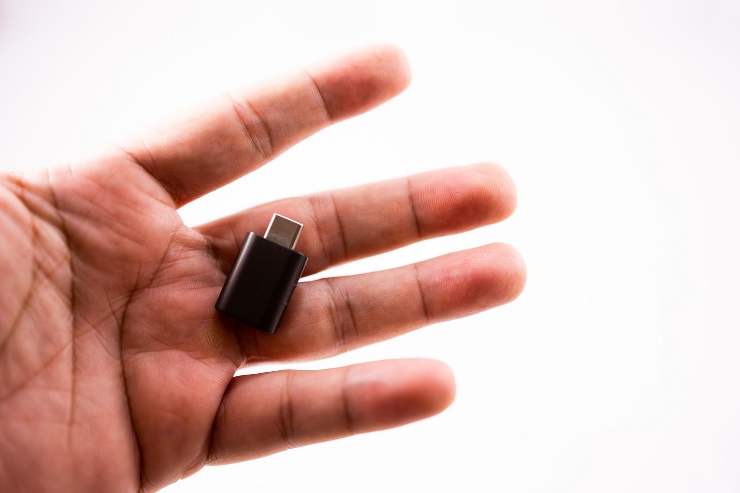 Mano sosteniendo una unidad flash USB compacta, representando los dispositivos extraíbles que pueden iniciar procesos de instalación en Windows.