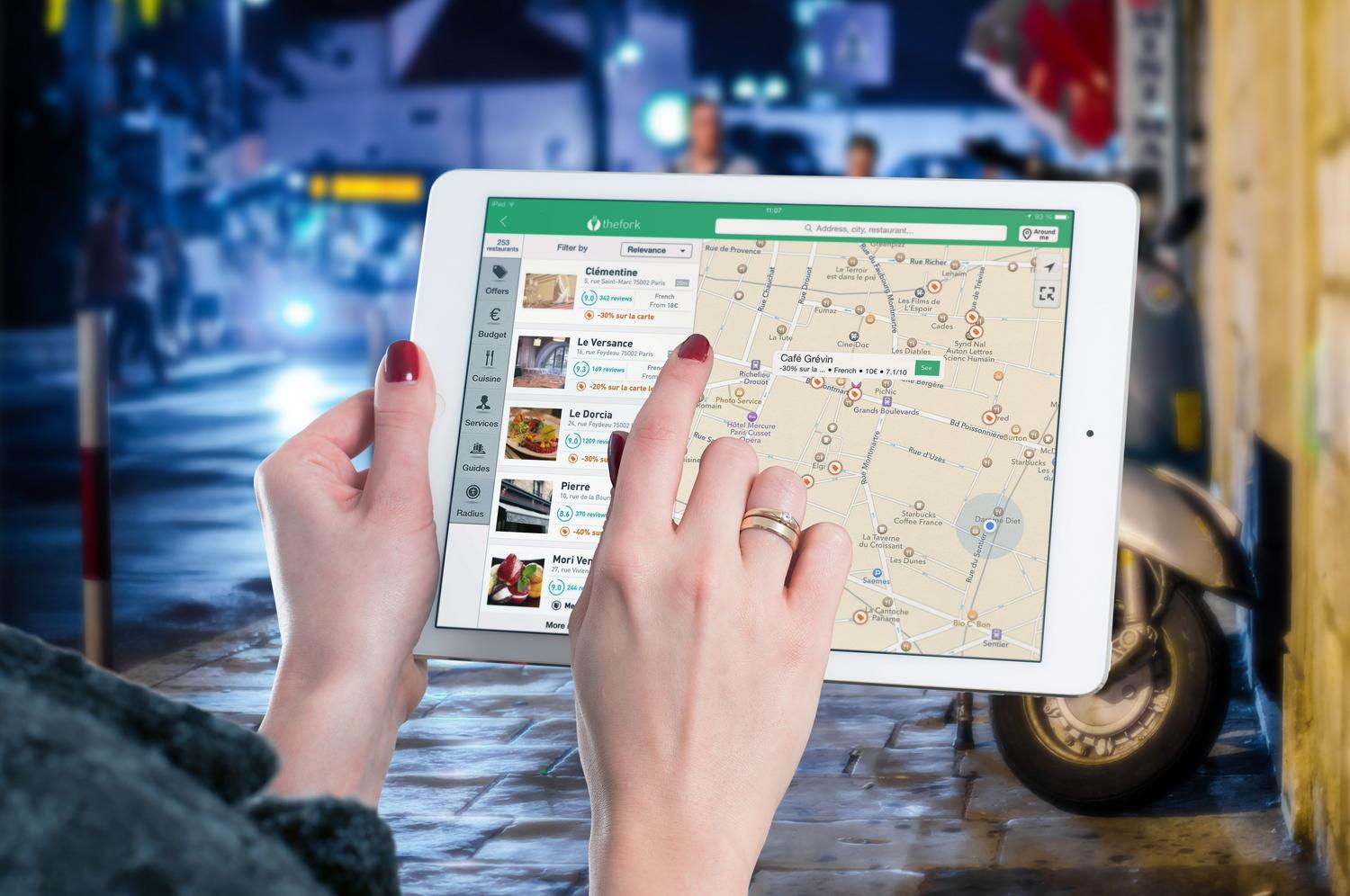 Uso de un mapa digital en una tablet para ejemplificar las funciones de navegación y búsqueda de lugares cercanos basadas en geolocalización.