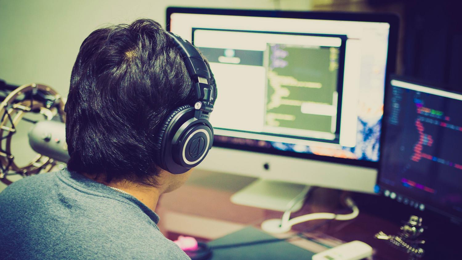 Programador trabajando en una estación de trabajo avanzada con múltiples monitores y equipo profesional.