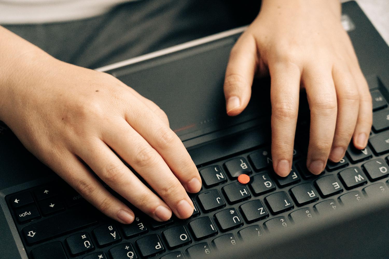 Manos escribiendo en un teclado de laptop, representando la interacción del usuario y la entrada de texto en el sistema.