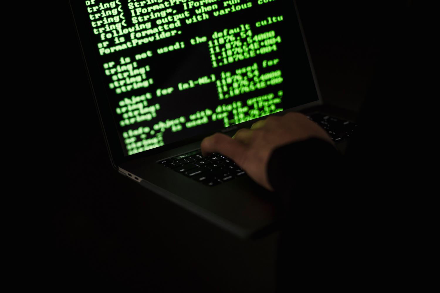 Persona escribiendo en un portátil en la oscuridad, representando las amenazas de malware, troyanos y la seguridad frente a intrusos.