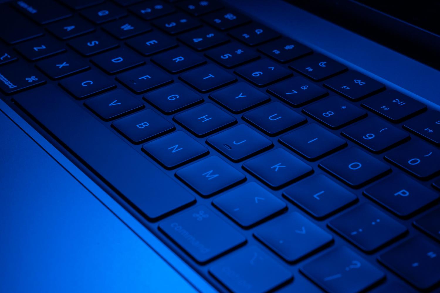 Teclado moderno iluminado con luz azul, proporcionando un contexto tecnológico para la explicación de procesos de Windows.