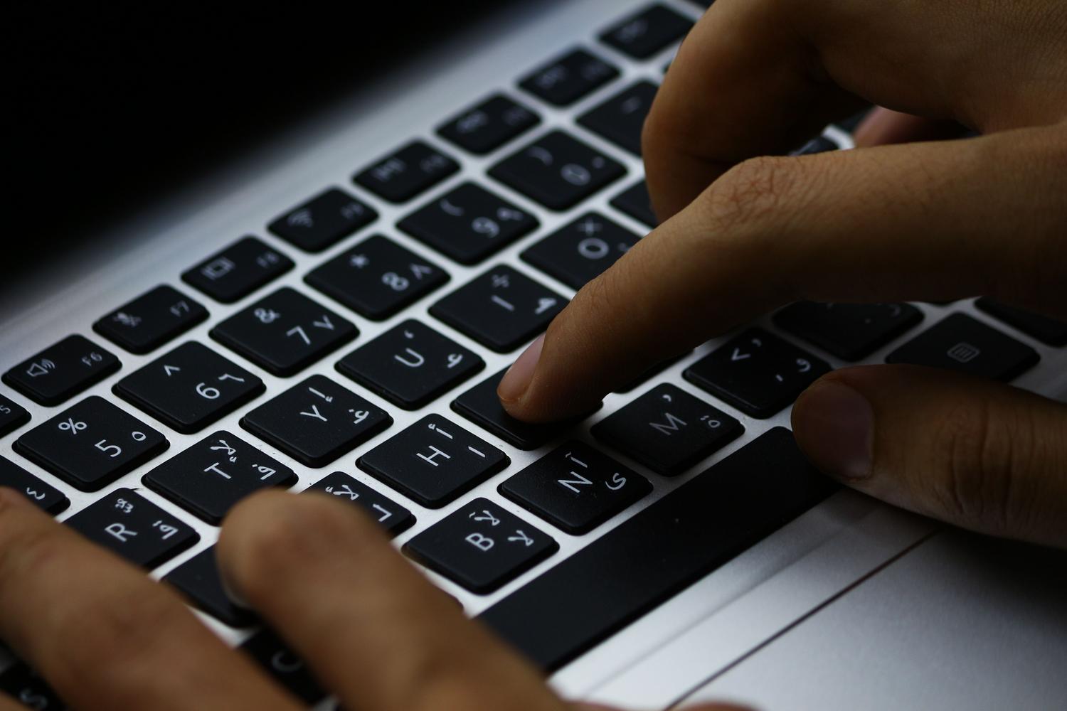Primer plano de manos escribiendo en un teclado con caracteres árabes, ilustrando la función de entrada de texto alternativa de ctfmon.exe.