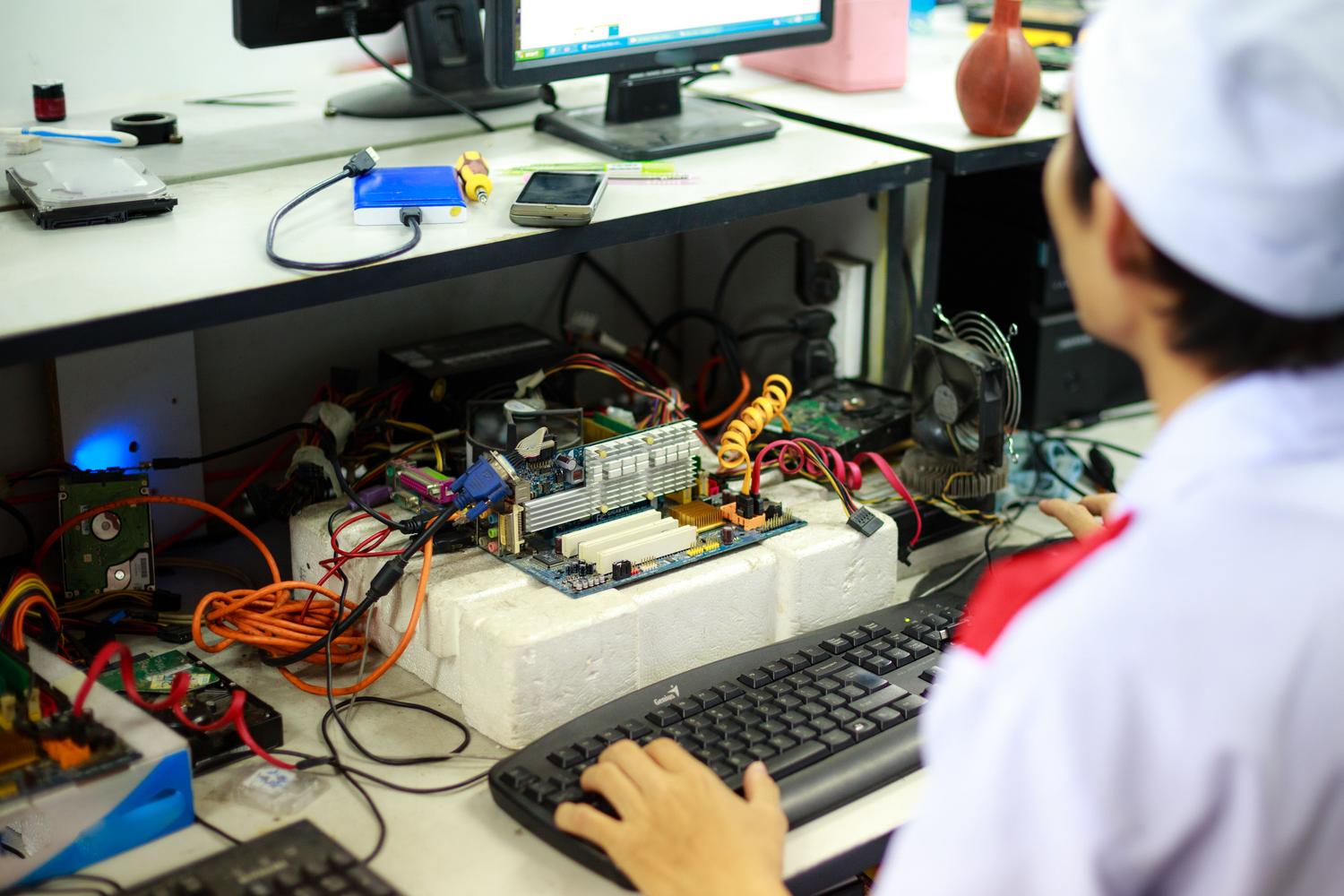 Técnico informático trabajando en el diagnóstico de una placa base en un entorno de laboratorio, representando el mantenimiento y reparación del sistema