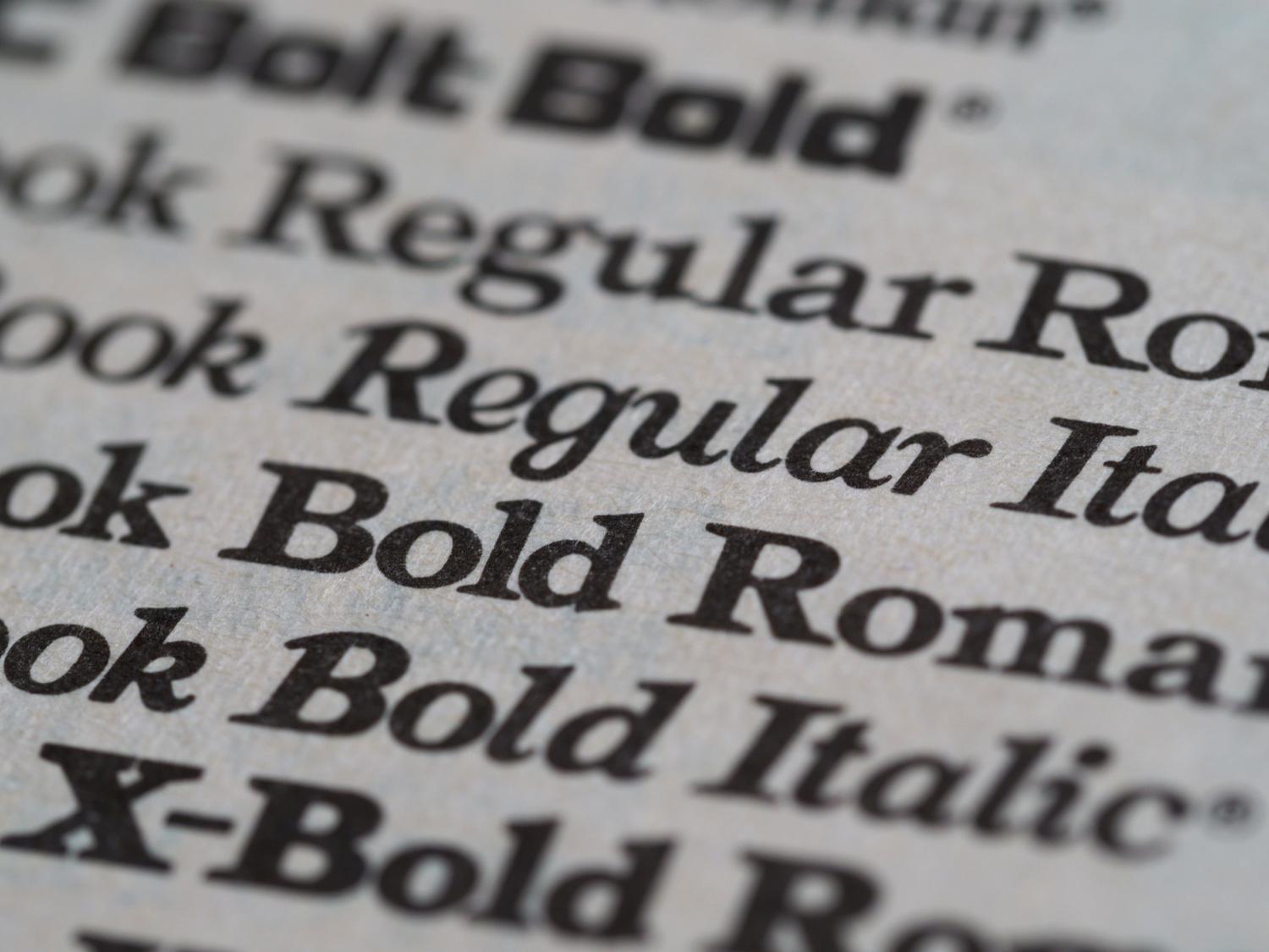 Detalle macro de diferentes estilos de tipografía impresa en papel, representando la función de renderizado de fuentes de fontdrvhost.exe.