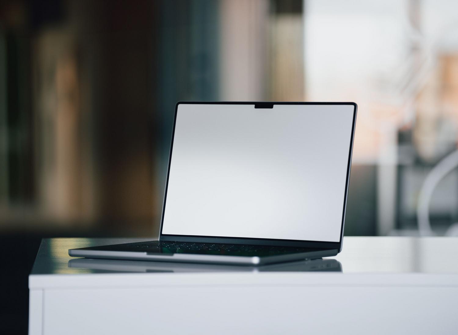 Espacio de trabajo minimalista con un portátil sobre un escritorio blanco, representando la seguridad silenciosa del sistema.