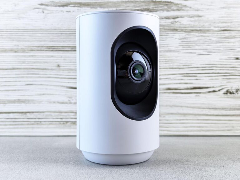 Cámara de seguridad inteligente para interiores sobre una superficie de madera, representando el hardware RTSP necesario.
