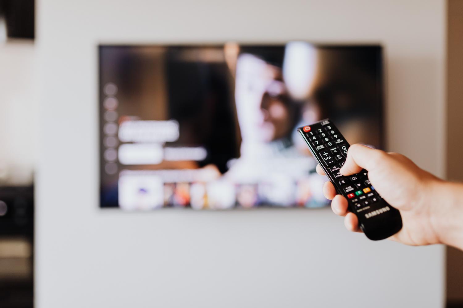 Persona utilizando un mando a distancia para seleccionar un podcast de vídeo en el televisor.