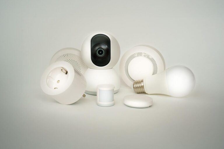 Colección de dispositivos IoT como bombillas, enchufes y cámaras inteligentes sobre un fondo blanco.