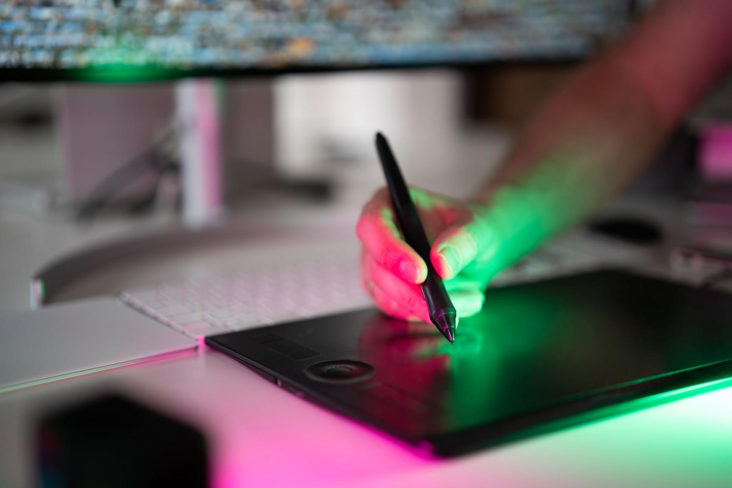 Mano utilizando un lápiz digital sobre una tableta gráfica, simbolizando la creación y edición de imágenes mediante IA generativa de Adobe Firefly en archivos PDF.