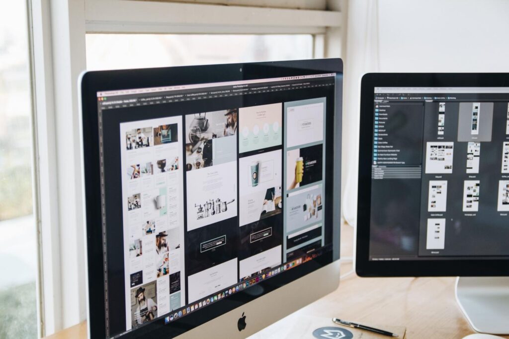 Escritorio de oficina moderno con monitores duales mostrando software de diseño gráfico.