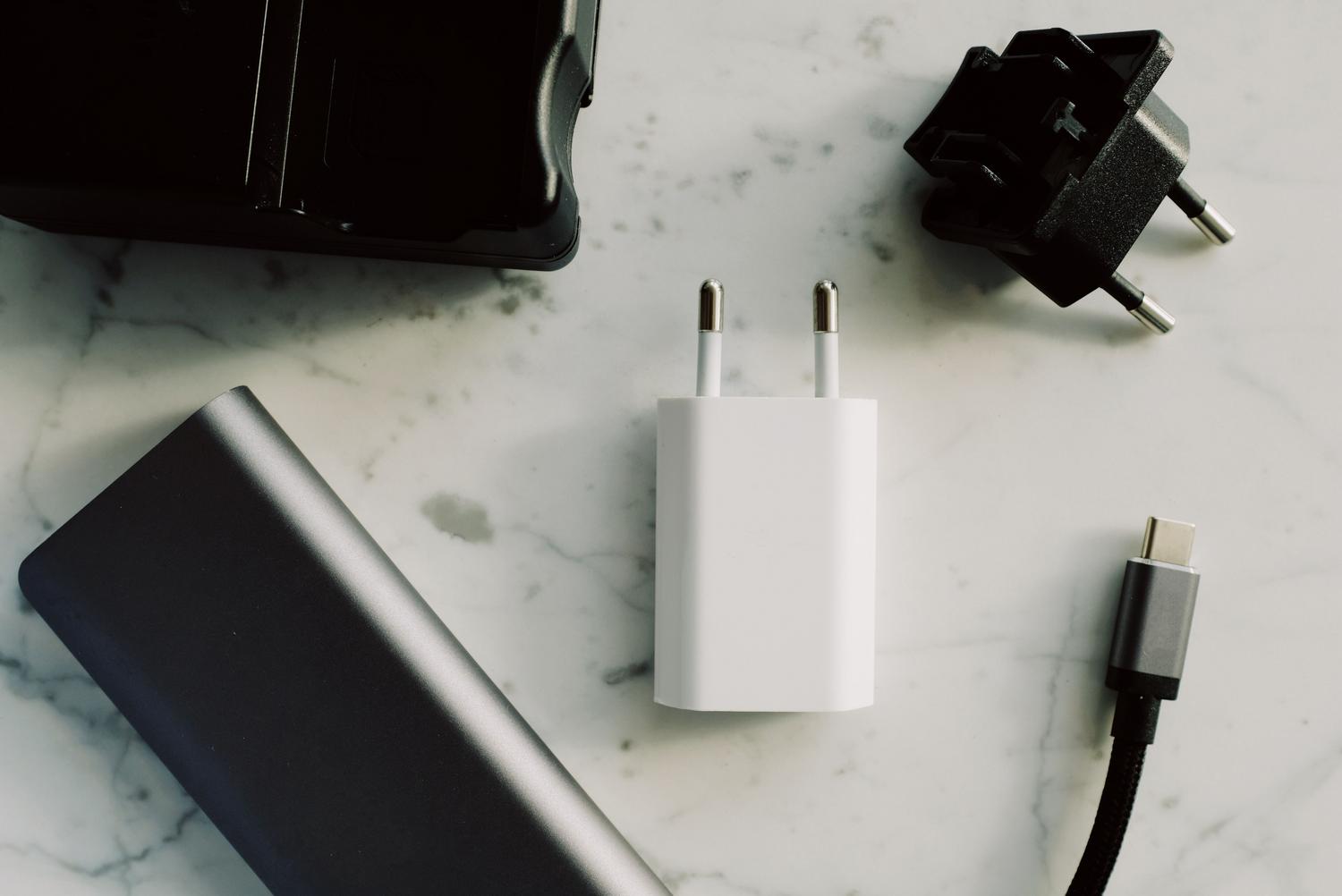 Variedad de cargadores, adaptadores y cables USB-C sobre una superficie de mármol, representando el estándar universal de carga.