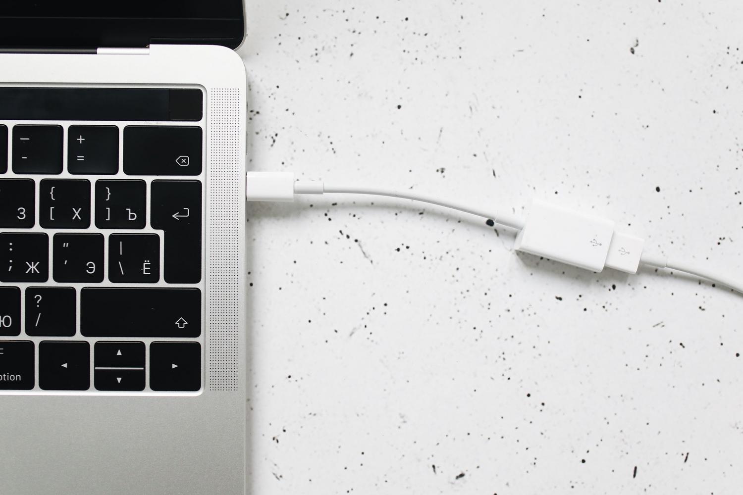 Cable USB-C conectado al puerto de carga de un ordenador portátil, ilustrando la alimentación de dispositivos de alta potencia.