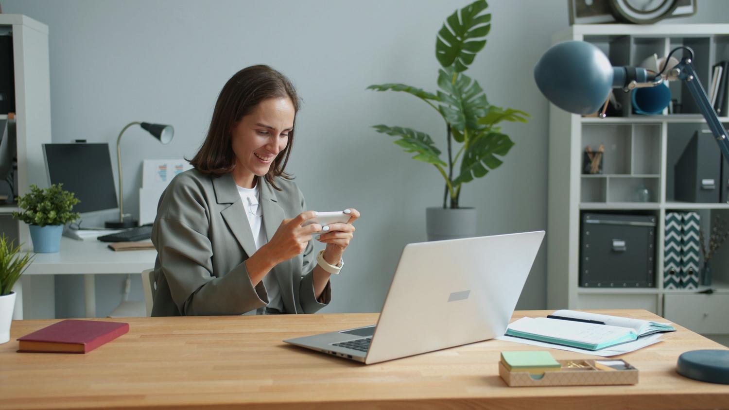 Mujer preparando el móvil y el ordenador para continuar una llamada de WhatsApp en otro dispositivo