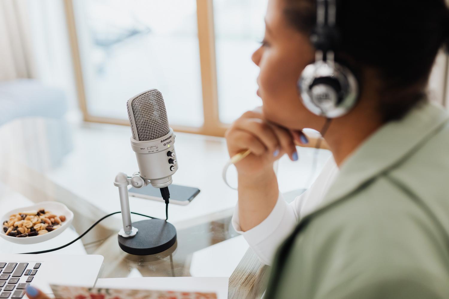 Persona utilizando un micrófono y auriculares frente a un ordenador.