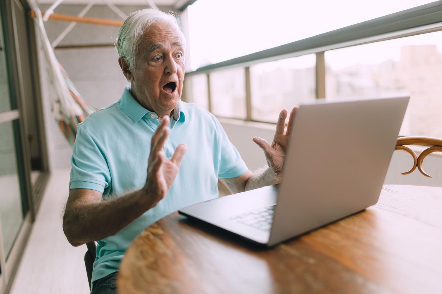 An elderly man with an expression of astonishment and surprise as he looks at his personal computer screen, illustrating the initial reaction to seeing an unexpected administrative message.