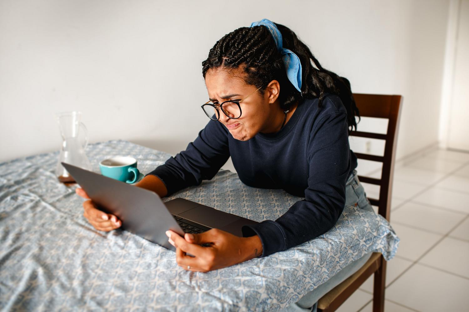A focused and slightly annoyed young woman is checking her computer settings at home, ideal for the section on causes of warnings on personal PCs.