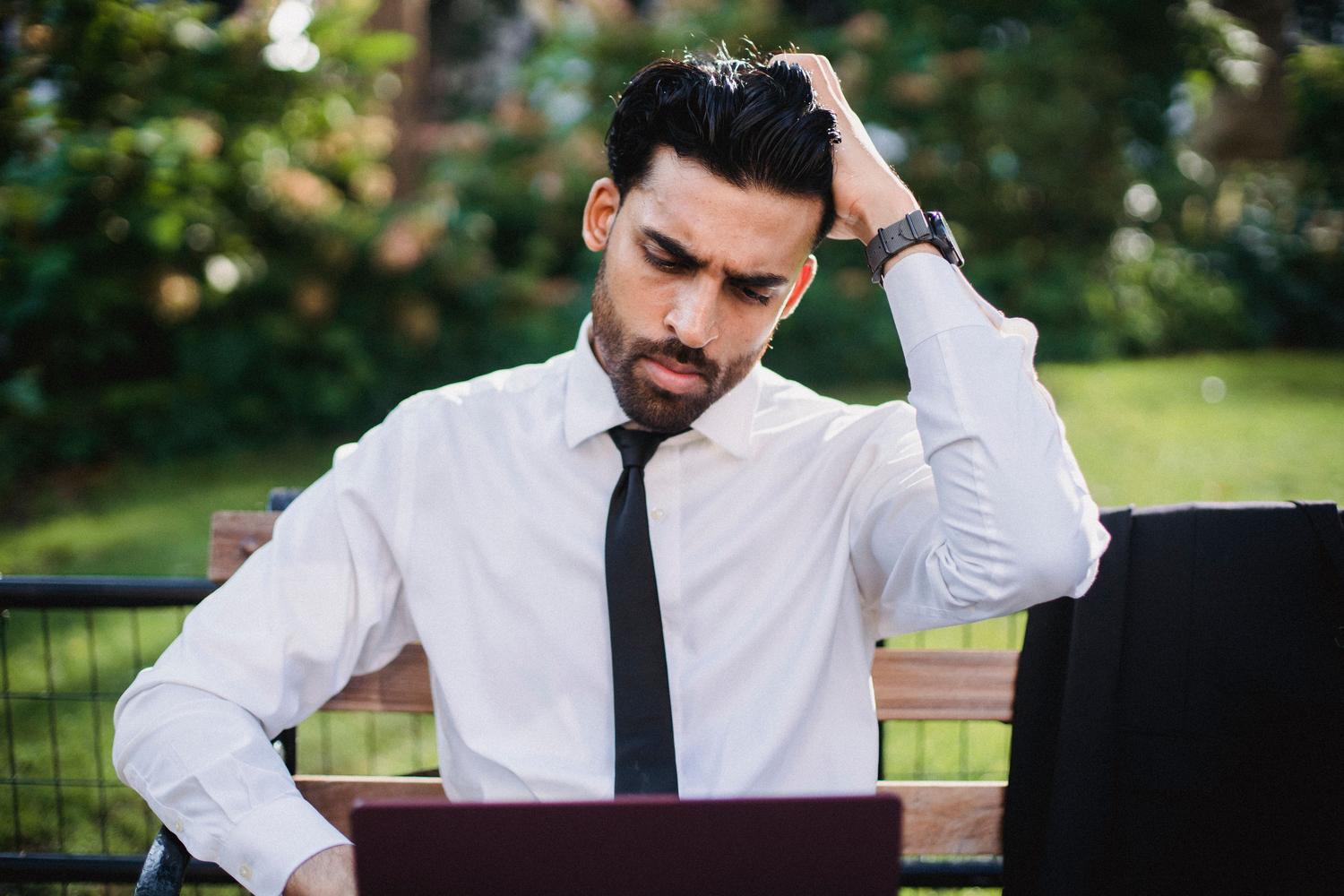 Man in professional attire troubleshooting on his laptop with a doubtful expression, representing the investigation and verification phase of Chrome policies.