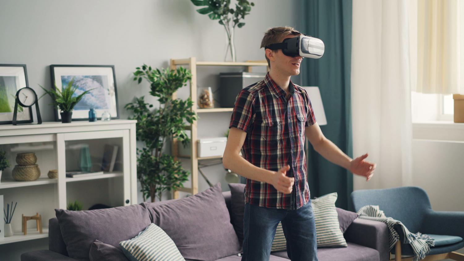 Hombre usando un casco de RV genérico en su salón, con los brazos extendidos interactuando con el aire, ideal para representar el escaneo de una habitación.