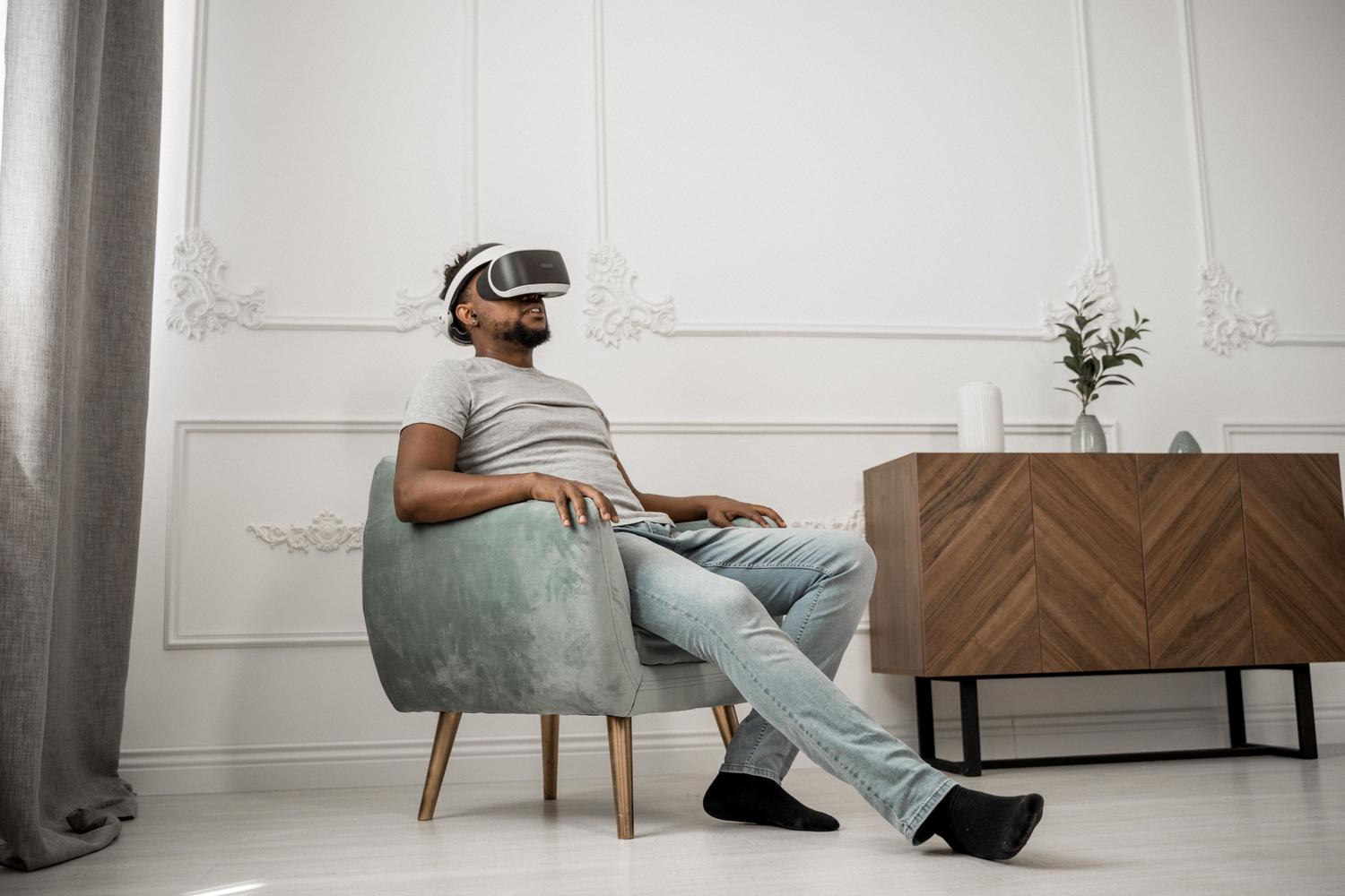 Hombre relajado en un salón moderno usando gafas de realidad virtual blancas, representando la configuración de un dispositivo de RA/RV en casa.