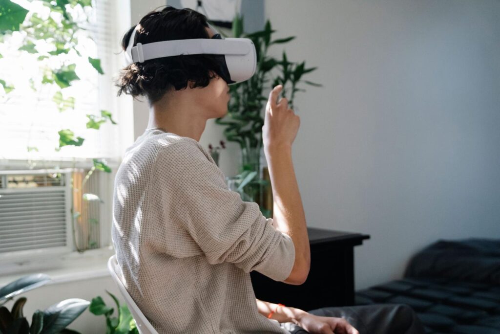 Persona utilizando gafas de realidad virtual en un salón iluminado, interactuando con el entorno virtual mediante gestos manuales.