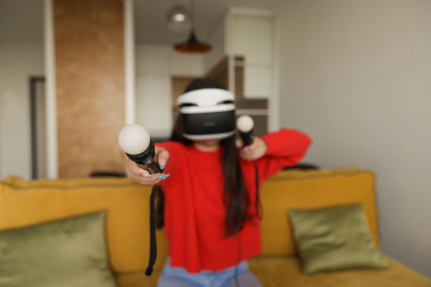 Mujer con visor de realidad virtual y mandos en una sala de estar, simulando la interacción y el mapeo de un espacio doméstico.