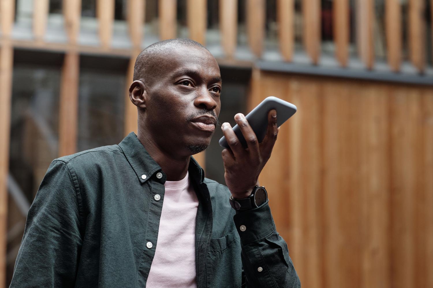 Hombre utilizando comandos de voz en su teléfono móvil en un entorno urbano moderno.