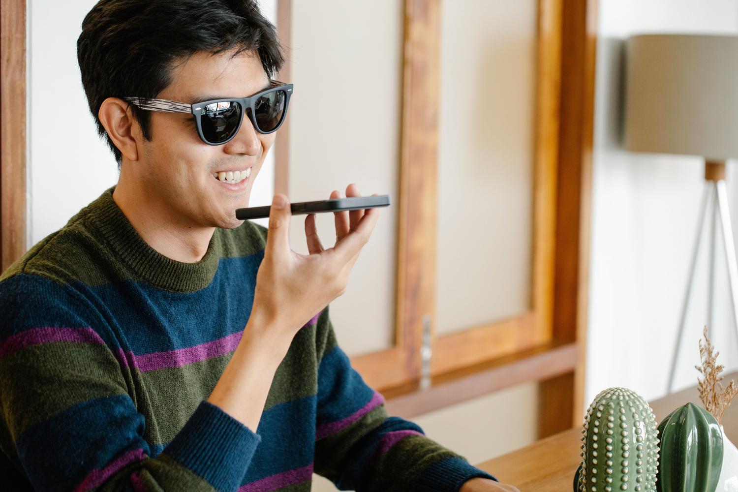 Joven utilizando las funciones de voz de su smartphone en un interior luminoso.