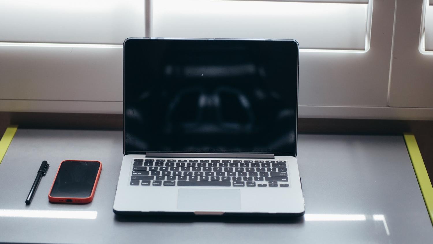 Escritorio minimalista con ordenador portátil y móvil, ideal para un flujo de trabajo organizado entre Android y macOS.