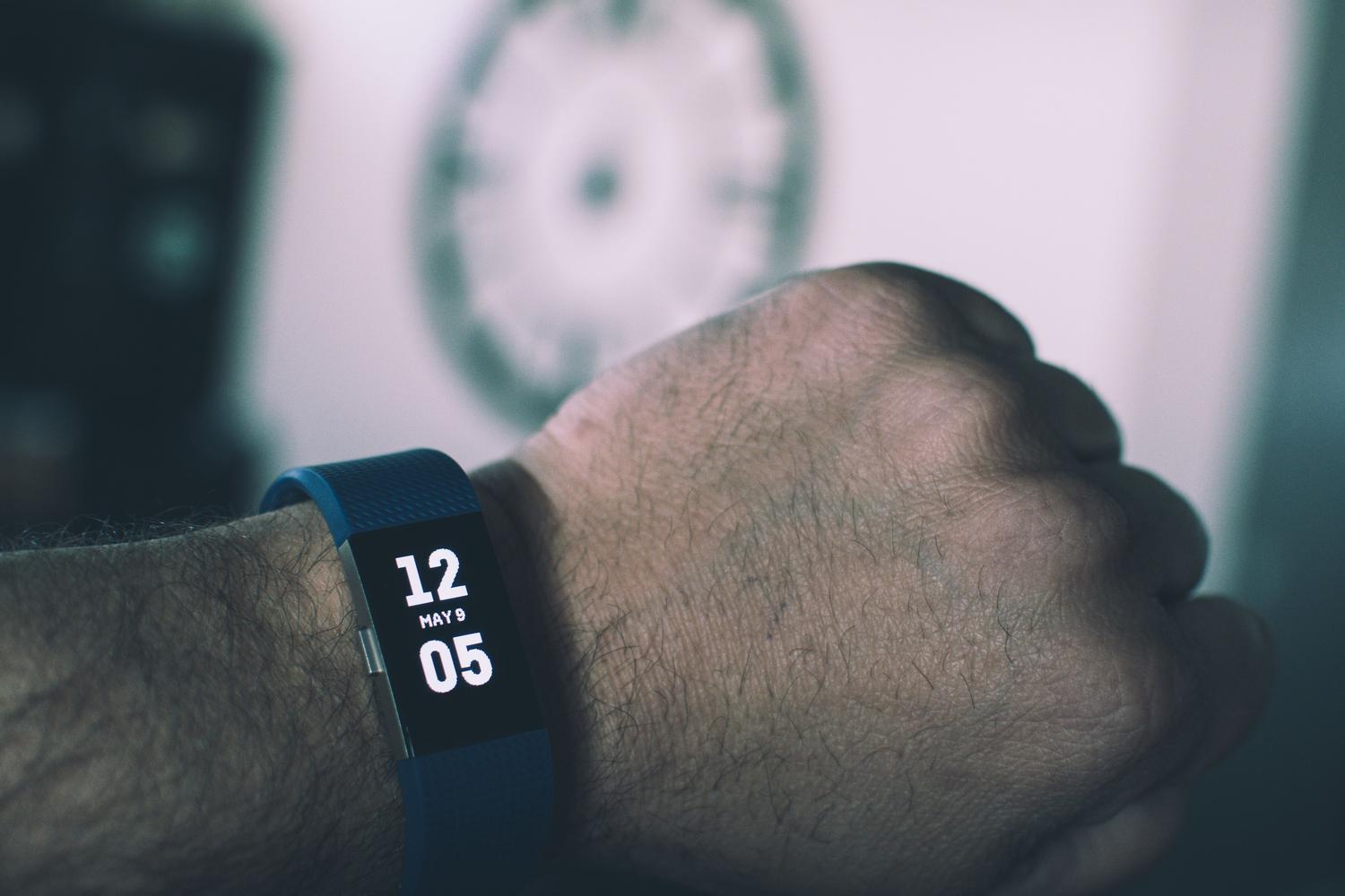 Primer plano de una pulsera de actividad inteligente en la muñeca de un hombre, ideal para ilustrar el uso de dispositivos Fitbit.