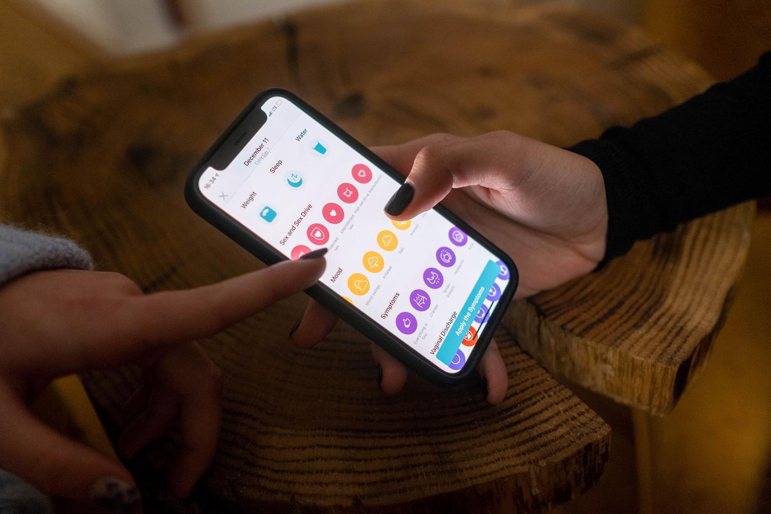 Manos utilizando una aplicación de seguimiento de salud en un teléfono móvil para monitorizar el bienestar.