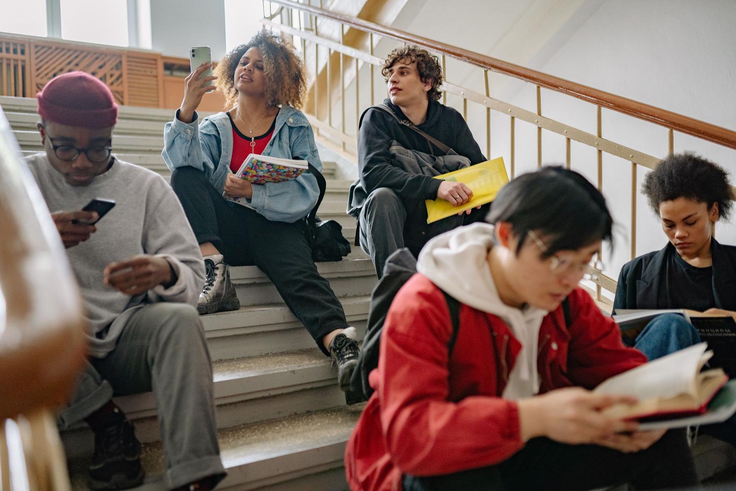 Estudiantes universitarios conviviendo y usando sus smartphones en las escaleras del campus.