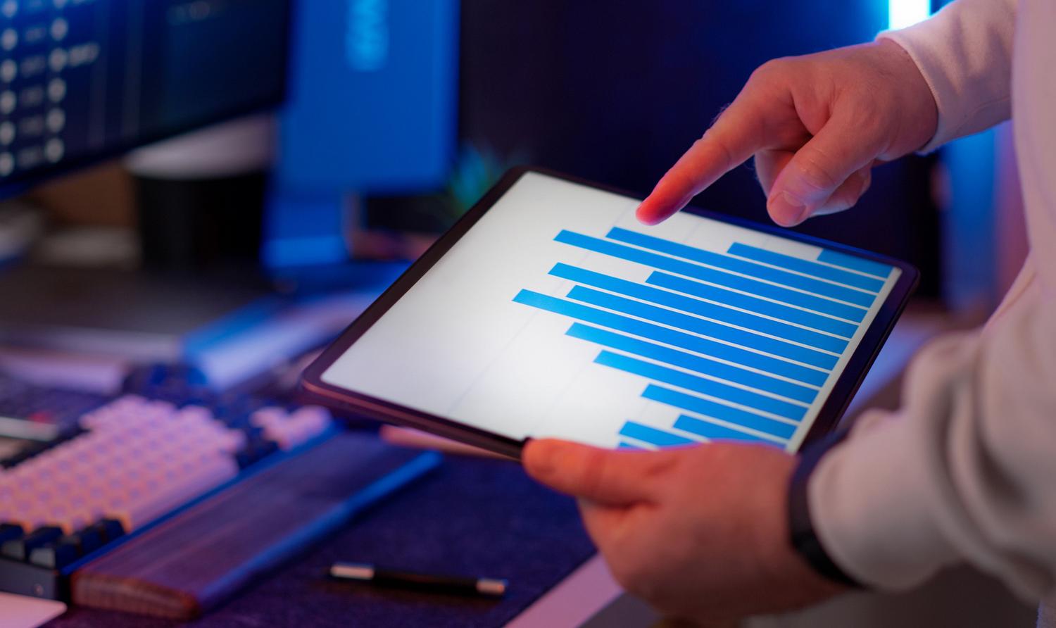 Profesional de negocios analizando un gráfico de barras en una tablet, destacando la utilidad de las visualizaciones claras para la toma de decisiones.