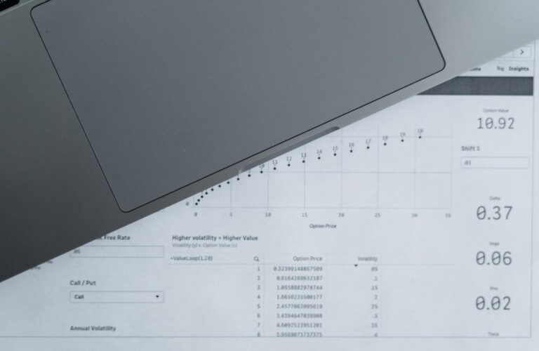 Vista cenital de hojas de datos analíticos y un ordenador portátil, representando el punto de partida de los datos en Excel.