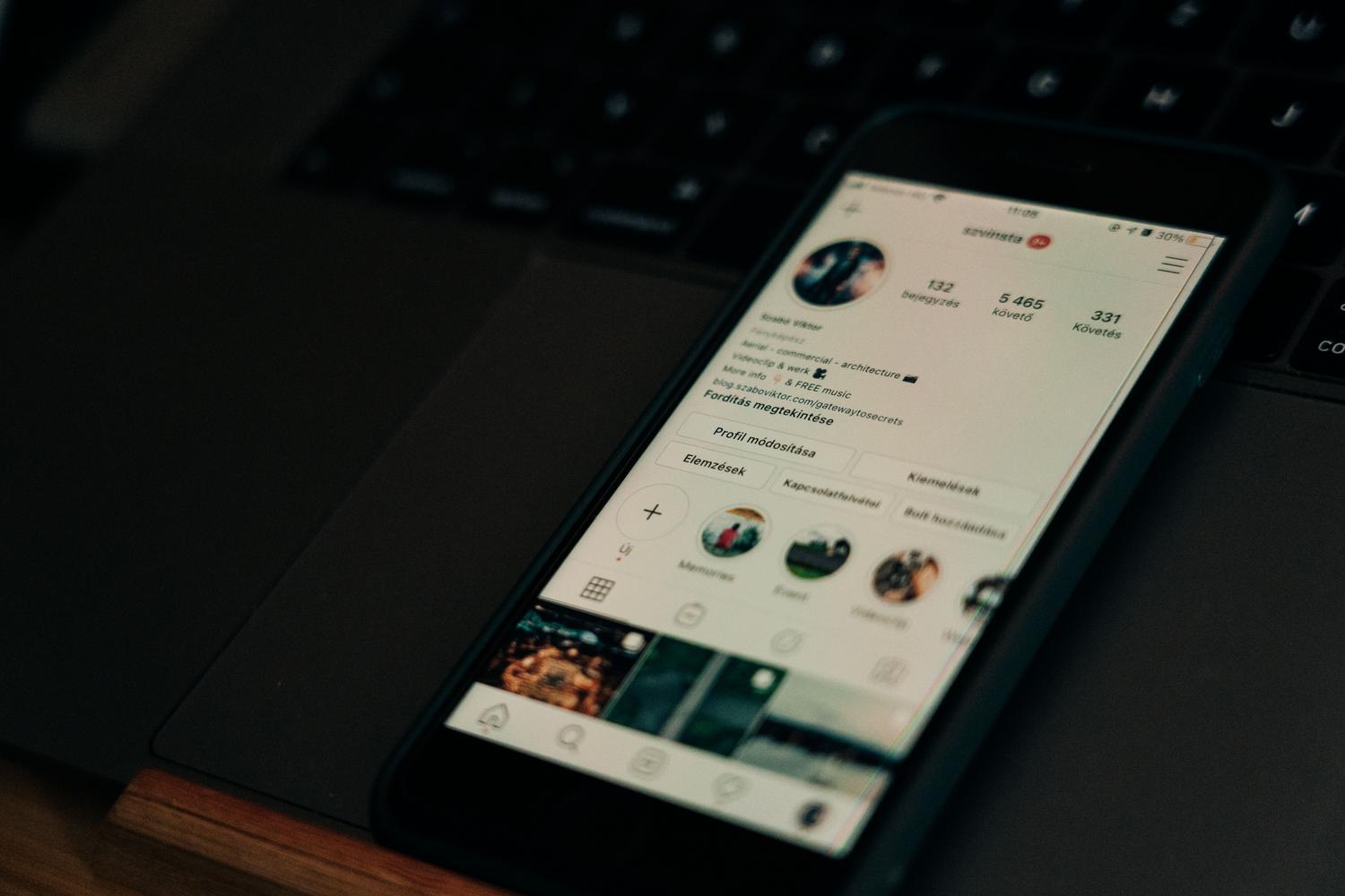 Smartphone sobre un ordenador portátil mostrando un perfil profesional, representando la gestión de contenidos para creadores y marcas.
