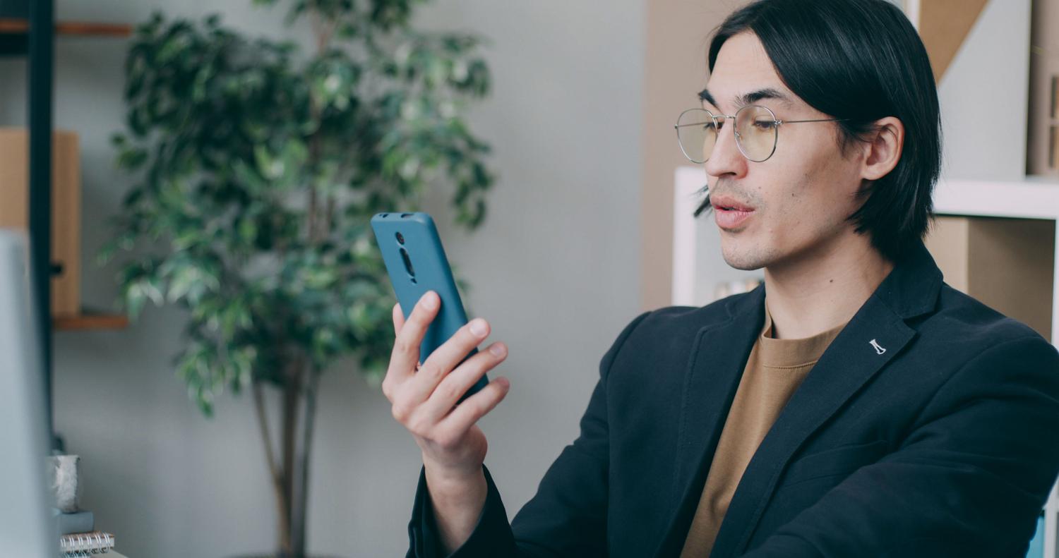 Profesional concentrado usando su teléfono móvil en una oficina moderna, representando el uso de herramientas de traducción para creadores.