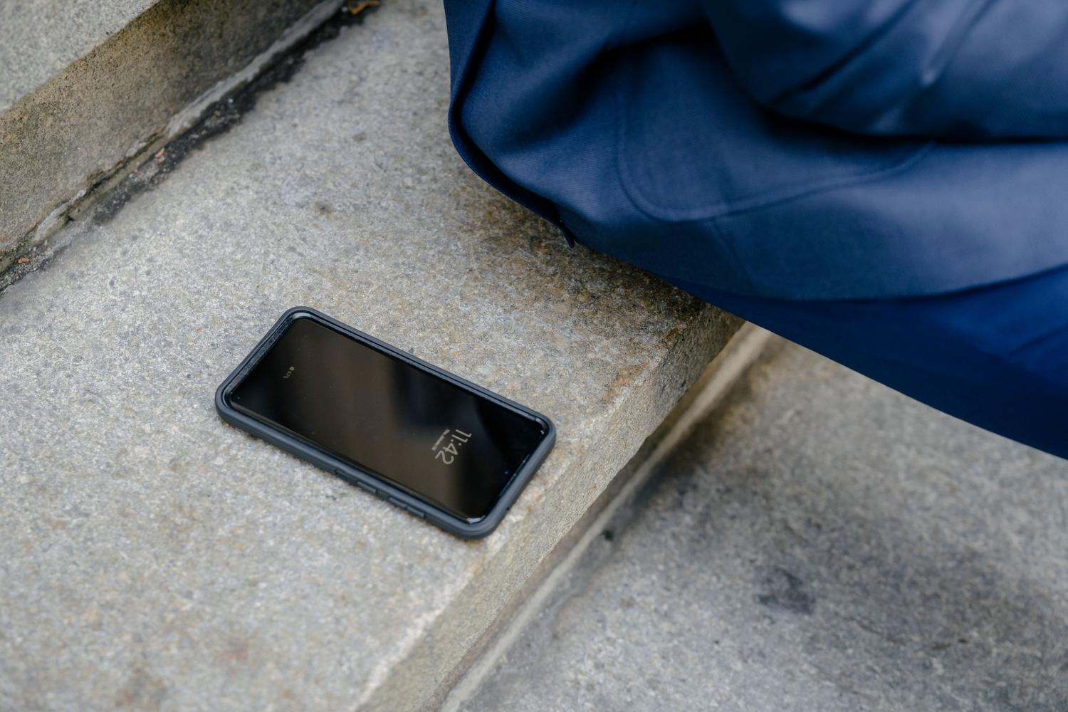 Teléfono inteligente olvidado en unos escalones de piedra, ilustrando un dispositivo extraviado.