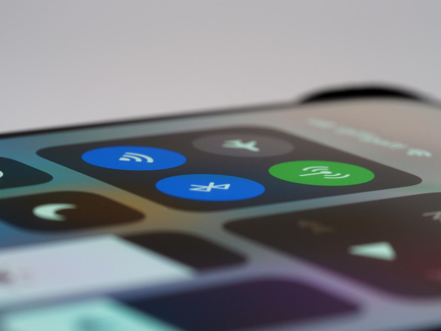 Detalle de la pantalla de un móvil mostrando los iconos de conexión Bluetooth y Wi-Fi activos.