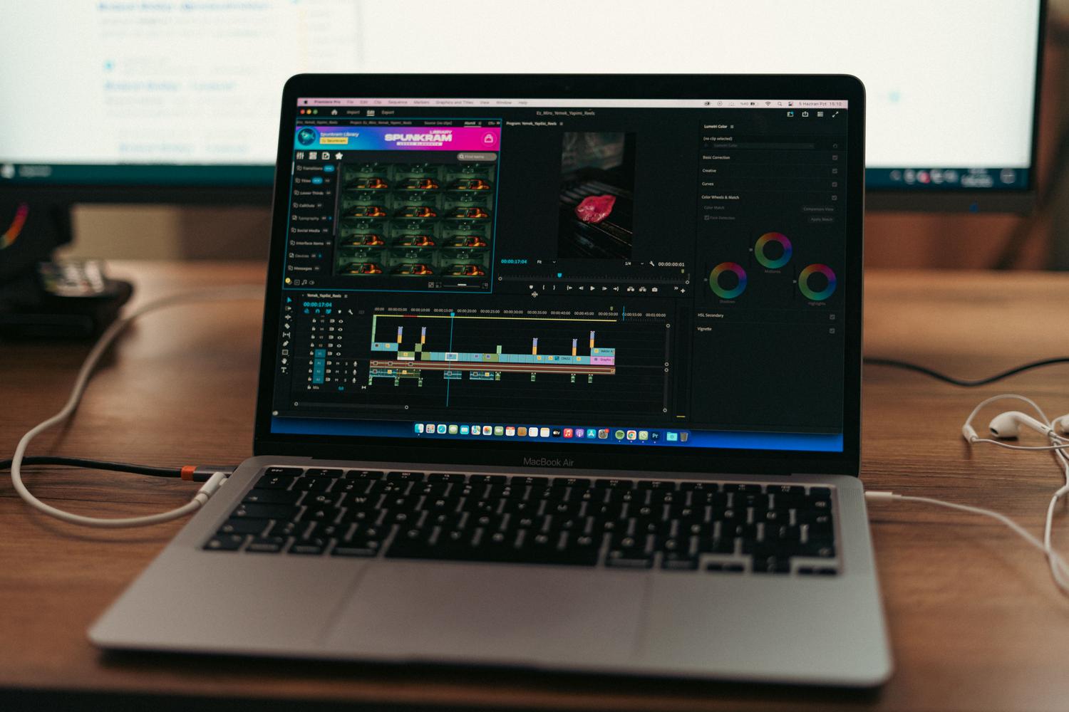 Entorno de trabajo creativo con MacBook Air, monitores externos y software de edición de vídeo.