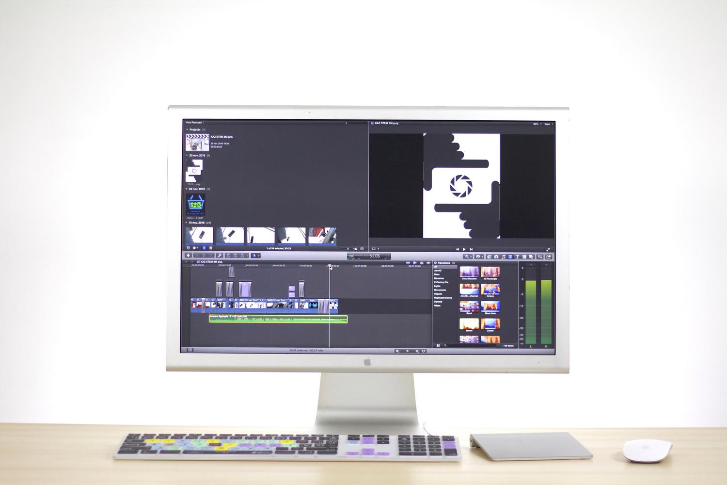 Espacio de trabajo minimalista y profesional con un iMac ejecutando software de edición de vídeo.
