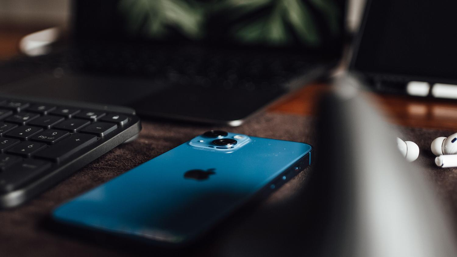 Escritorio de trabajo organizado con un iPhone, portátil y accesorios, representando el ecosistema de Apple.