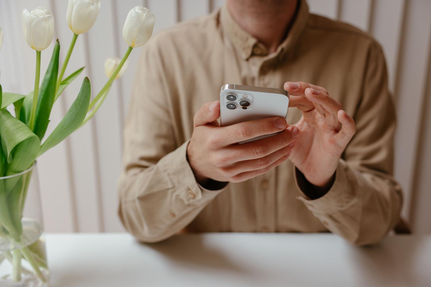 Primer plano de una persona gestionando tareas en un iPhone en un entorno de trabajo moderno y luminoso.
