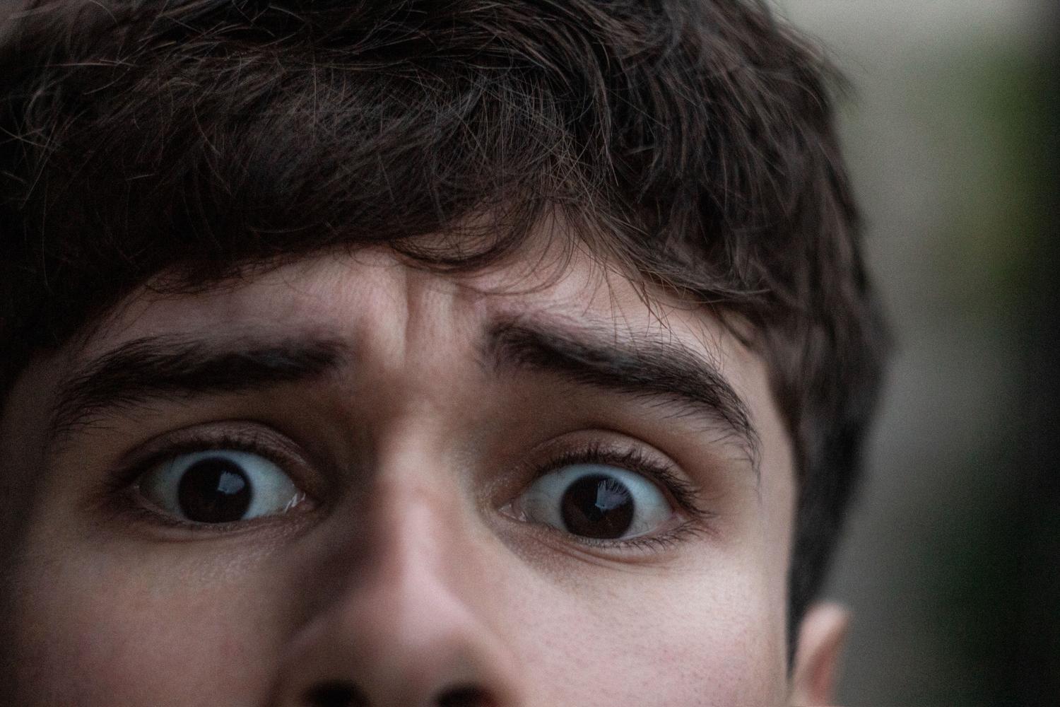 Primer plano de un hombre joven con expresión de shock y sorpresa extrema al escuchar un sonido inesperado.