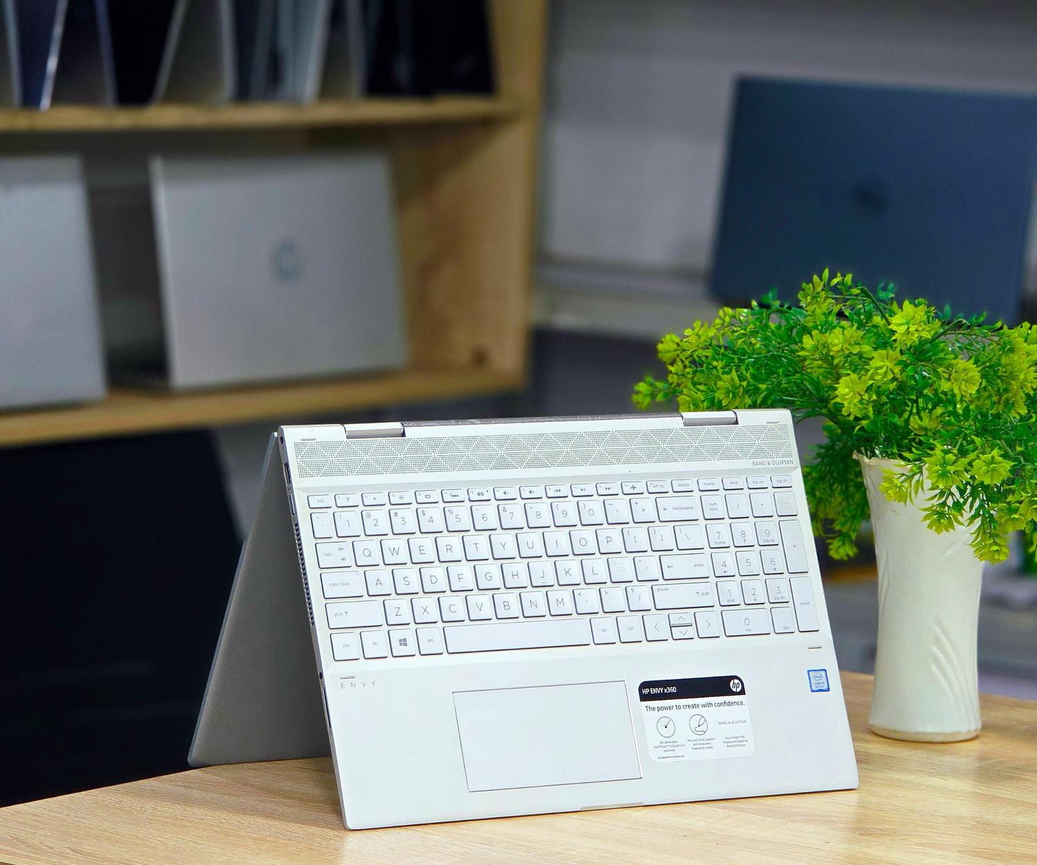Portátil convertible moderno sobre un escritorio de madera con una planta verde, ideal para ilustrar equipos híbridos. Chromebook Plus