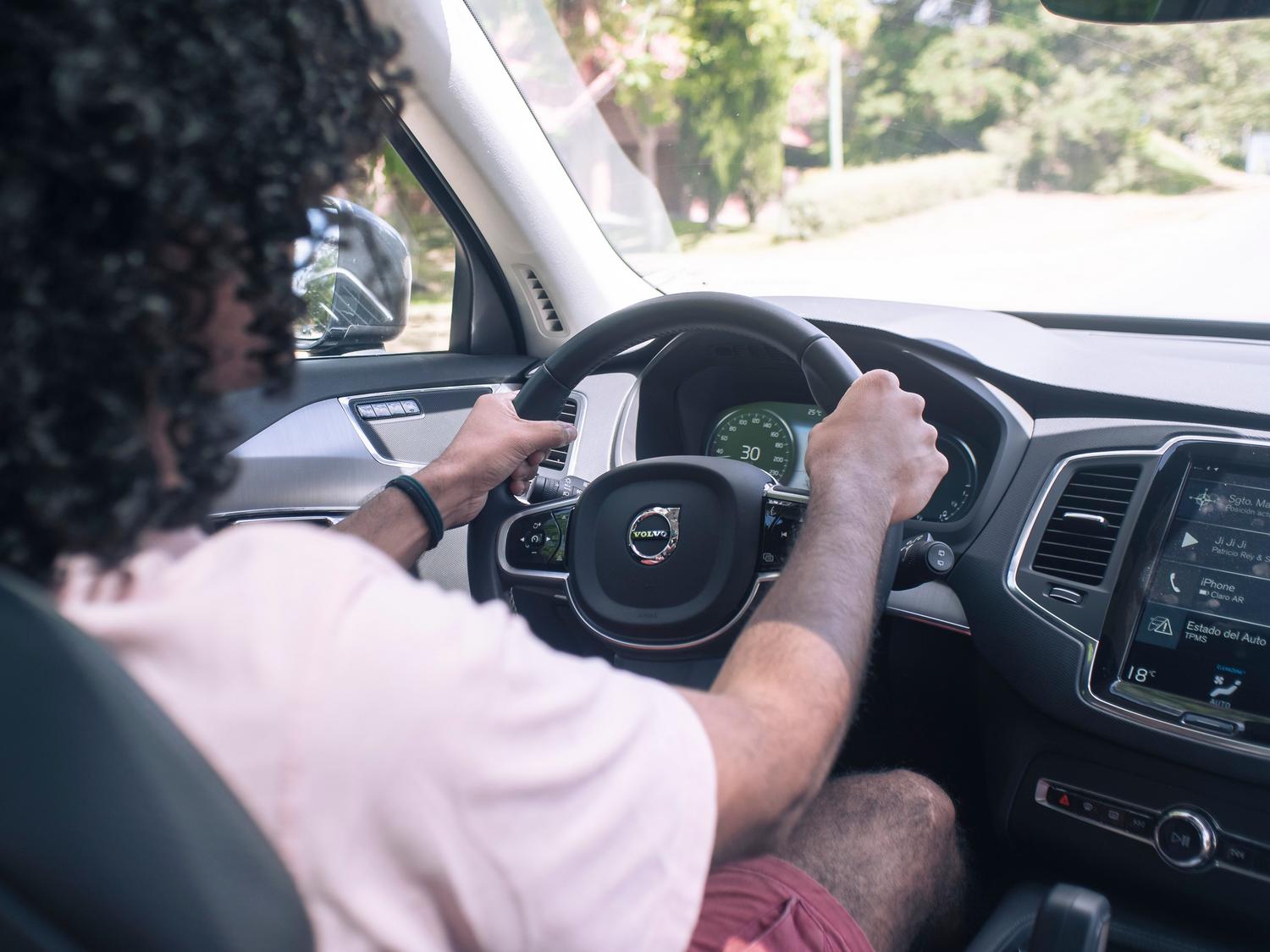 Conductor atento al volante de un coche moderno, representando la seguridad al utilizar asistentes de voz manos libres.