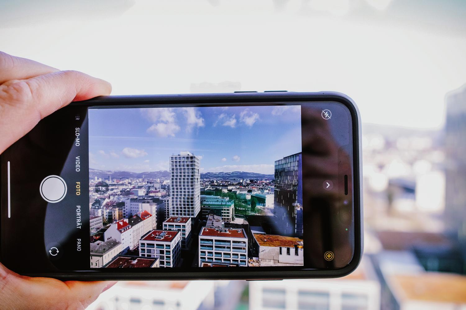 Primer plano de una mano sosteniendo un smartphone que encuadra un paisaje urbano, ilustrando la capacidad de analizar el mundo real en tiempo real con la cámara.