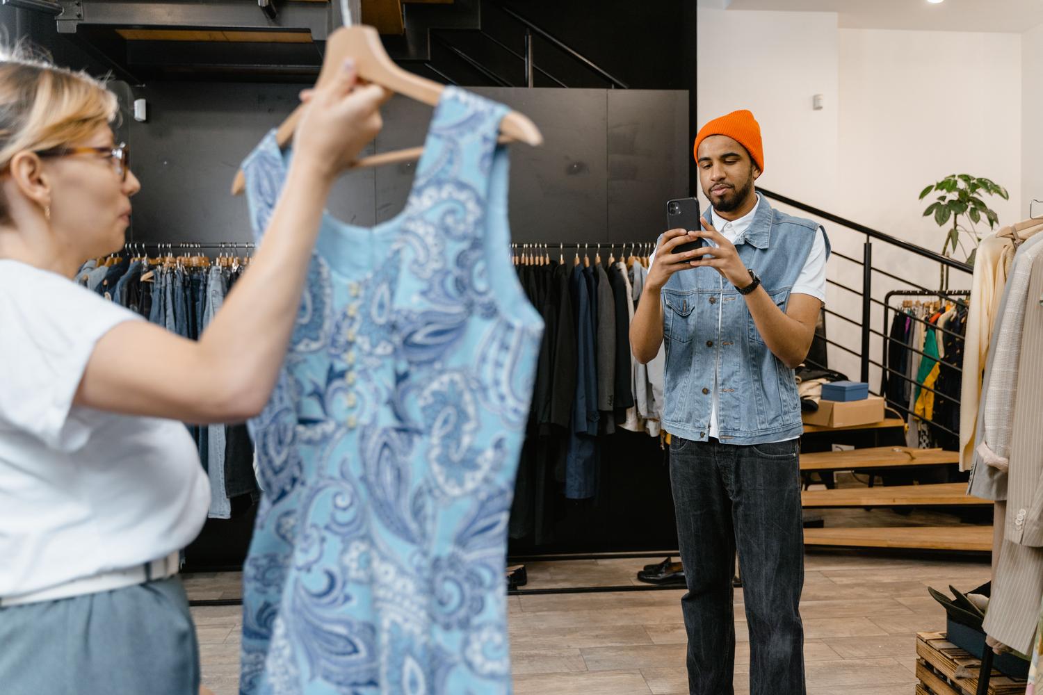 Hombre fotografiando una prenda de vestir en una tienda de moda, representando la función de búsqueda de ropa y 'Encuentra el look'.