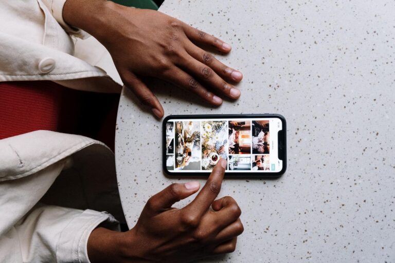 Persona utilizando un teléfono inteligente para editar fotografías en un entorno moderno y luminoso