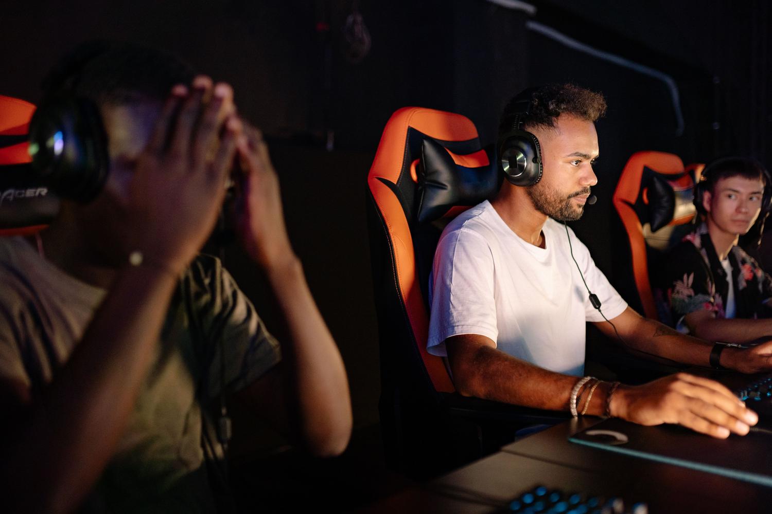 Grupo de tres jugadores con auriculares gaming en un entorno de esports, representando la comunicación en el chat de grupo.